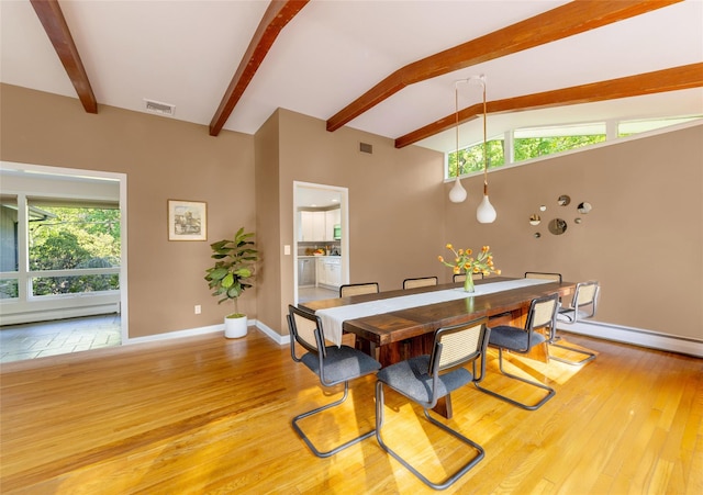 dining area featuring beam ceiling, light wood finished floors, baseboards, and a baseboard radiator