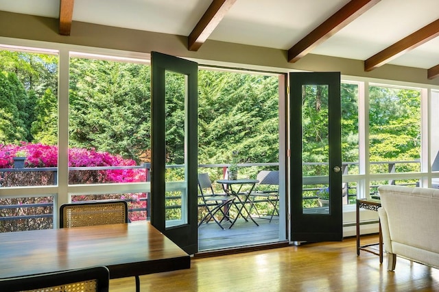 doorway to outside featuring beam ceiling, baseboard heating, wood finished floors, and plenty of natural light