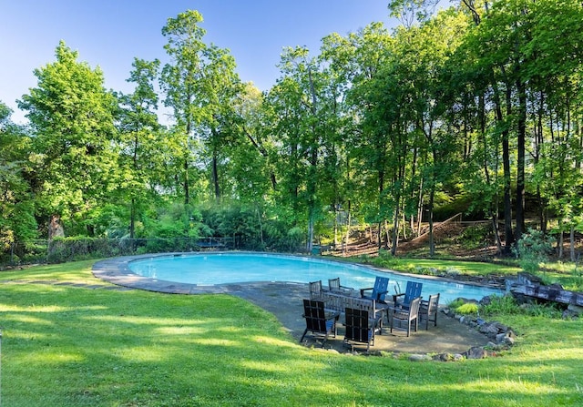 outdoor pool with a lawn, central AC, and view of scattered trees