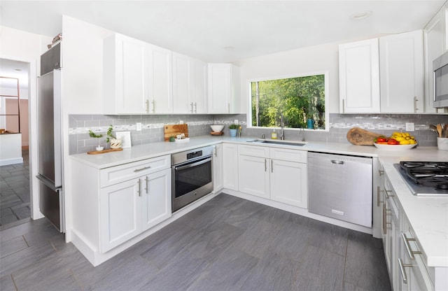 kitchen featuring stainless steel appliances, a sink, light countertops, and backsplash