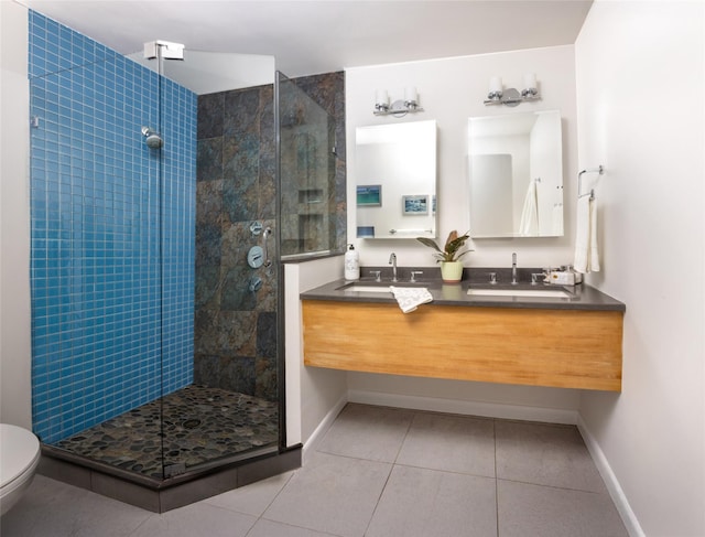 bathroom featuring a tile shower, tile patterned floors, toilet, baseboards, and double vanity