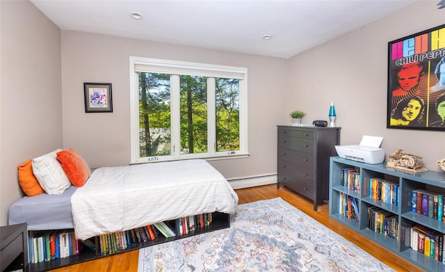 bedroom featuring a baseboard heating unit, wood finished floors, and recessed lighting
