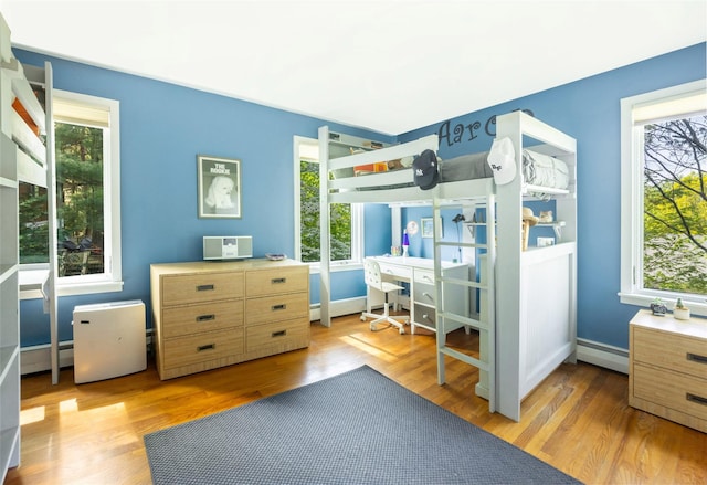 bedroom featuring multiple windows, an office area, and baseboard heating