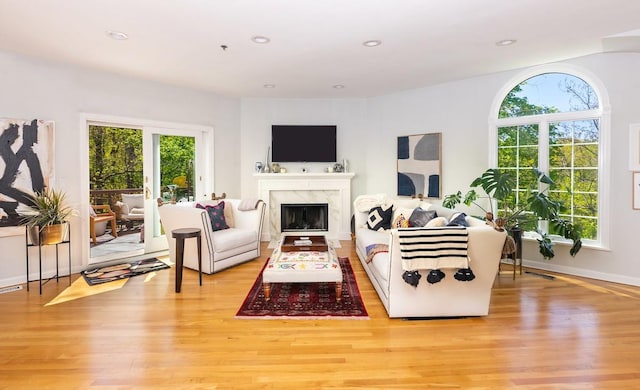 living room with light wood-type flooring, a fireplace, recessed lighting, and baseboards