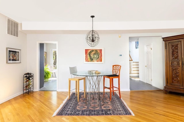 dining room featuring a chandelier, wood finished floors, stairs, and baseboards