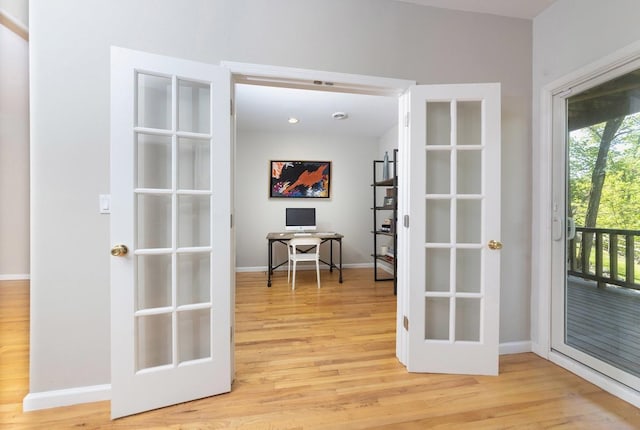 doorway to outside with light wood-type flooring, an office area, and baseboards