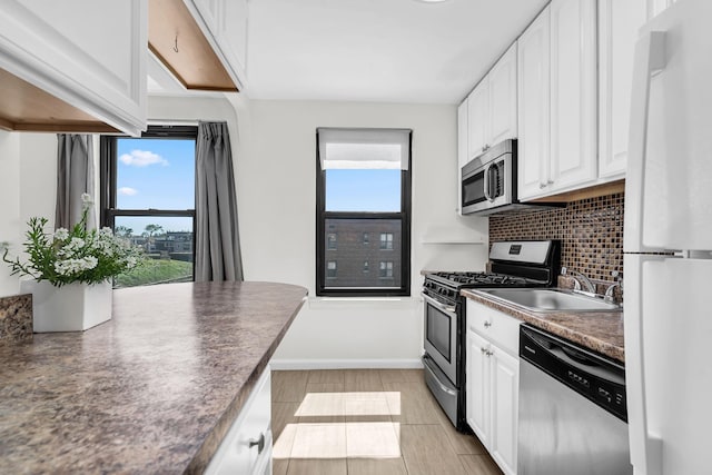 kitchen featuring dark countertops, tasteful backsplash, stainless steel appliances, and white cabinetry
