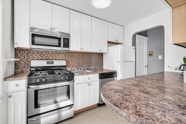kitchen with a sink, decorative backsplash, white cabinetry, and stainless steel appliances