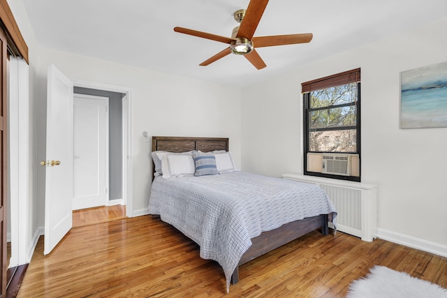 bedroom with ceiling fan, baseboards, cooling unit, radiator heating unit, and light wood-style flooring
