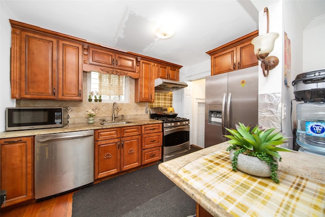 6 Walnut Pl, Great Neck, NY 11021 - kitchen with tasteful backsplash, a sink, brown cabinetry, stainless steel appliances, and under cabinet range hood