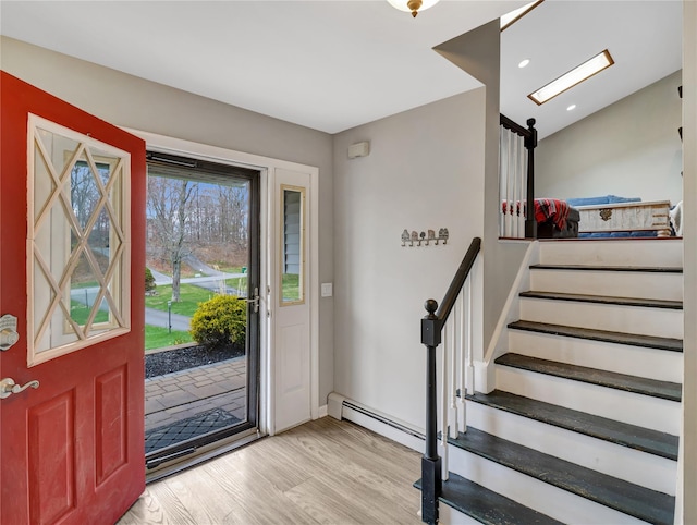 entryway featuring baseboards, wood finished floors, a baseboard radiator, and stairs