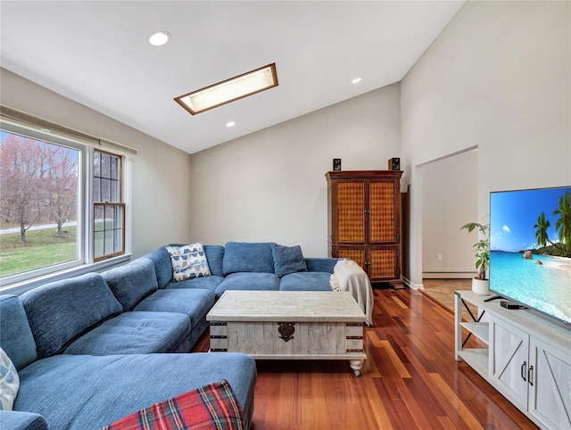 living room with dark wood finished floors, vaulted ceiling with skylight, a baseboard radiator, and recessed lighting