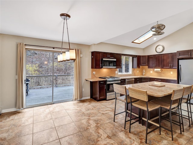 kitchen featuring lofted ceiling with skylight, appliances with stainless steel finishes, decorative backsplash, and a sink