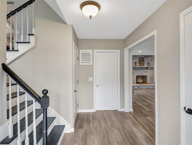 entrance foyer with baseboards, wood finished floors, a fireplace, and stairs