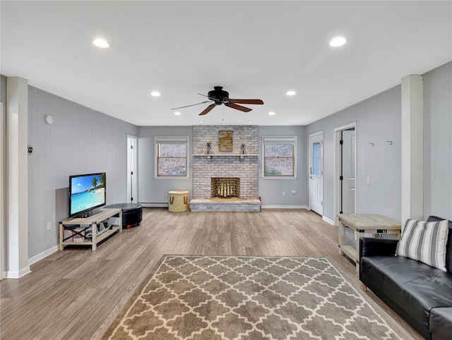 living room with a ceiling fan, wood finished floors, baseboards, a brick fireplace, and recessed lighting