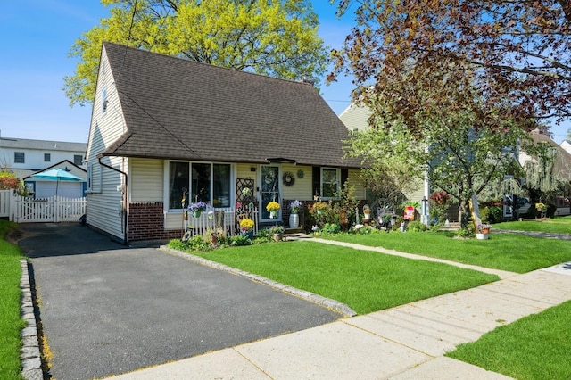 cape cod house featuring roof with shingles, fence, a porch, and a front yard