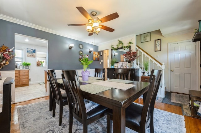dining area with crown molding, light wood-style floors, ceiling fan, and stairway