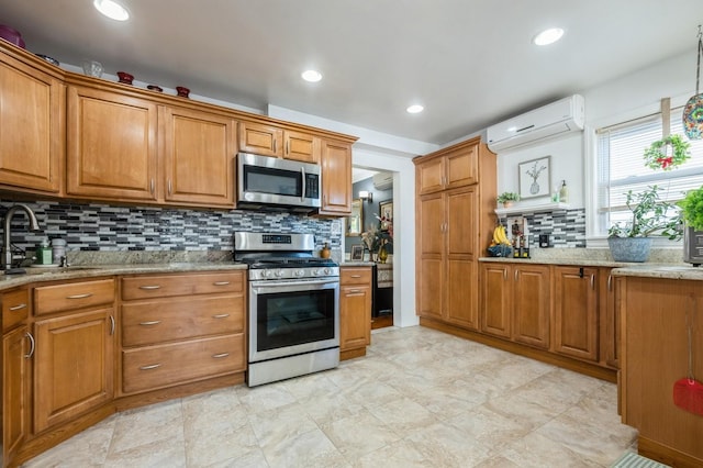 kitchen with brown cabinetry, backsplash, appliances with stainless steel finishes, a wall mounted AC, and a sink