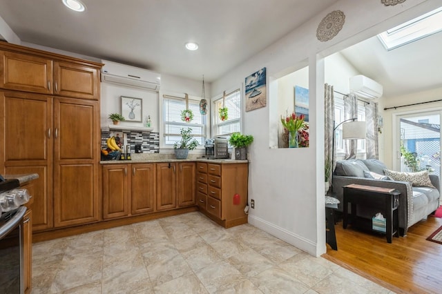 kitchen with a wall mounted AC, brown cabinets, a skylight, and a healthy amount of sunlight
