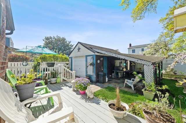 deck featuring an outdoor structure, a garage, fence, and a grill