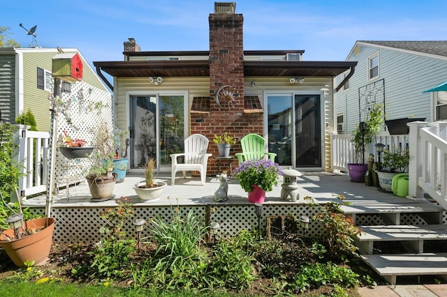 rear view of house featuring a deck, fence, and a chimney