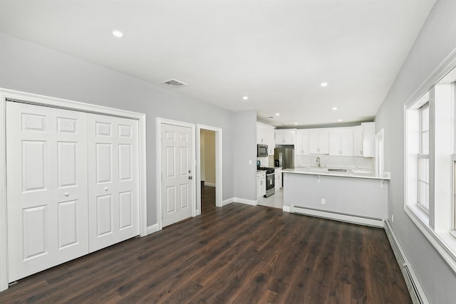 kitchen with stainless steel appliances, dark wood finished floors, visible vents, baseboard heating, and light countertops