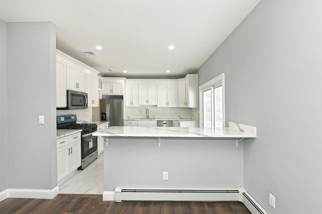 kitchen featuring stainless steel appliances, visible vents, a sink, a baseboard radiator, and white cabinetry