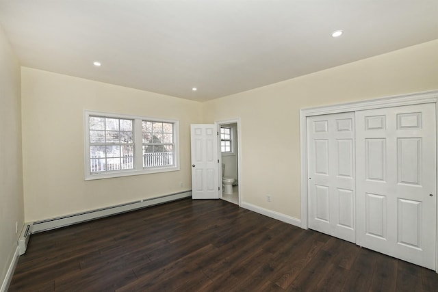 unfurnished bedroom with a baseboard radiator, baseboards, dark wood-type flooring, and a closet