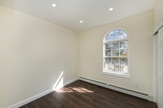 empty room with a baseboard heating unit, baseboards, dark wood-style flooring, and recessed lighting