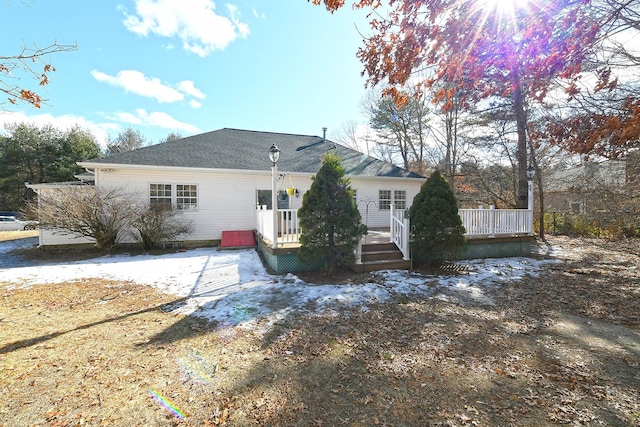 rear view of house with roof with shingles and a deck