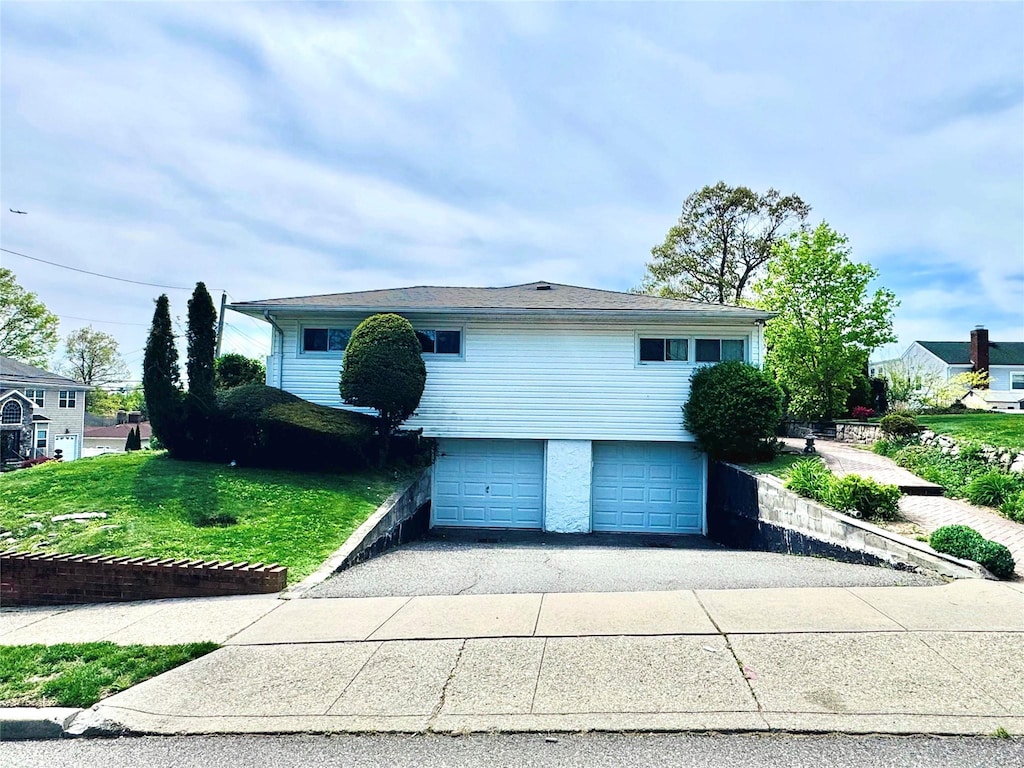 view of front of house with a garage, a front lawn, and driveway