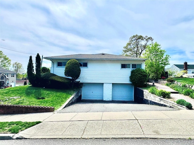 view of front of house with a garage, a front lawn, and driveway