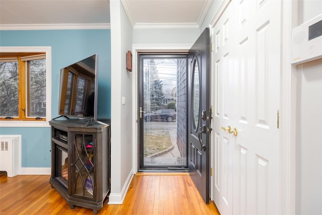 doorway to outside featuring ornamental molding, baseboards, radiator heating unit, and light wood-type flooring