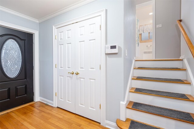 entrance foyer featuring light wood-type flooring, baseboards, stairs, and ornamental molding
