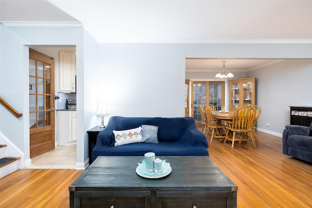 living room with stairway, crown molding, a chandelier, light wood finished floors, and baseboards