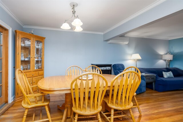 dining area featuring light wood-style flooring, a wall mounted AC, a notable chandelier, and crown molding