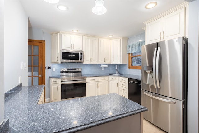 kitchen featuring recessed lighting, stainless steel appliances, dark stone countertops, a sink, and decorative backsplash