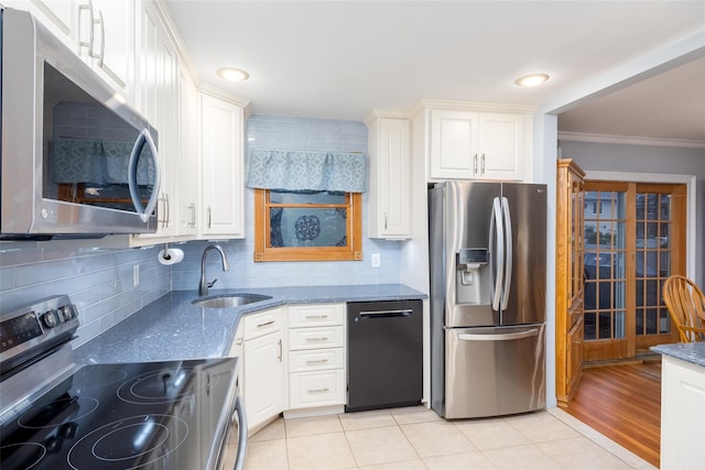 kitchen with a sink, dark stone counters, backsplash, crown molding, and appliances with stainless steel finishes