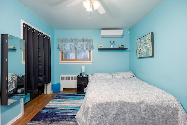 bedroom with radiator, a wall mounted AC, wood finished floors, and a ceiling fan