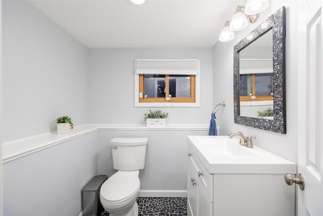 half bathroom with toilet, vanity, and baseboards