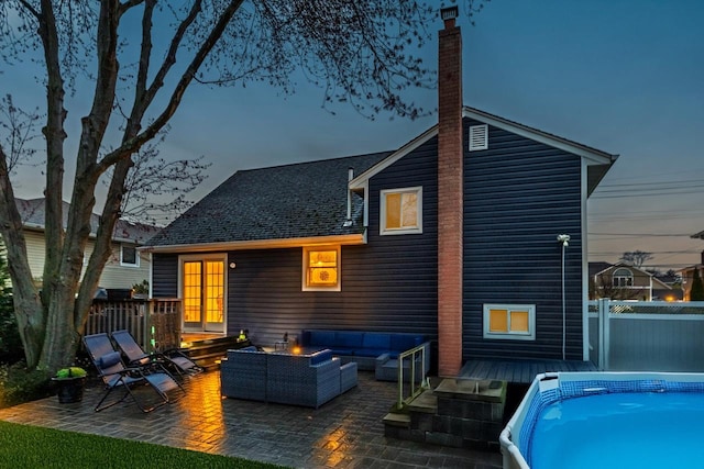 rear view of house with a chimney, fence, a wooden deck, outdoor lounge area, and a patio area