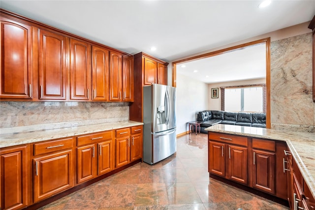 kitchen featuring light stone countertops, decorative backsplash, stainless steel fridge, and recessed lighting
