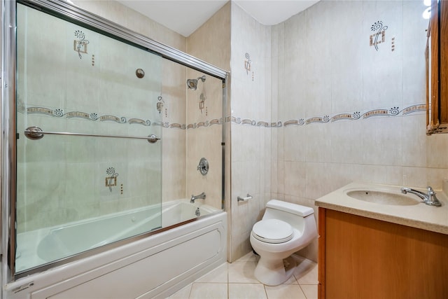full bath with toilet, tile walls, tile patterned flooring, vanity, and enclosed tub / shower combo