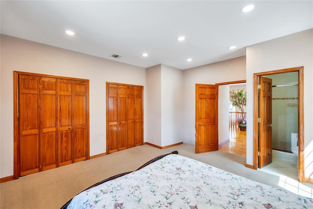 bedroom featuring recessed lighting, multiple closets, and light colored carpet