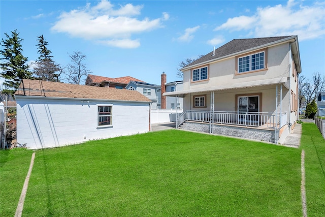 rear view of property with fence, a lawn, and stucco siding
