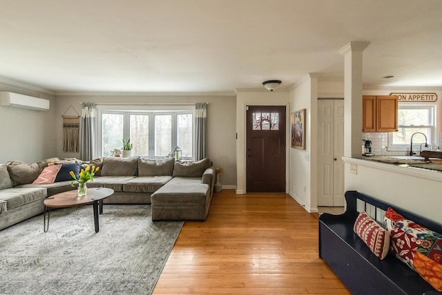 37 Rural Ave, Wingdale, NY 12594 - living room featuring a wall mounted air conditioner, baseboards, light wood finished floors, ornamental molding, and ornate columns