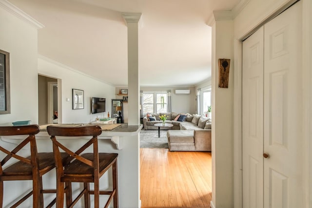 37 Rural Ave, Wingdale, NY 12594 - kitchen with light wood-style floors, ornamental molding, a breakfast bar, and a wall mounted air conditioner