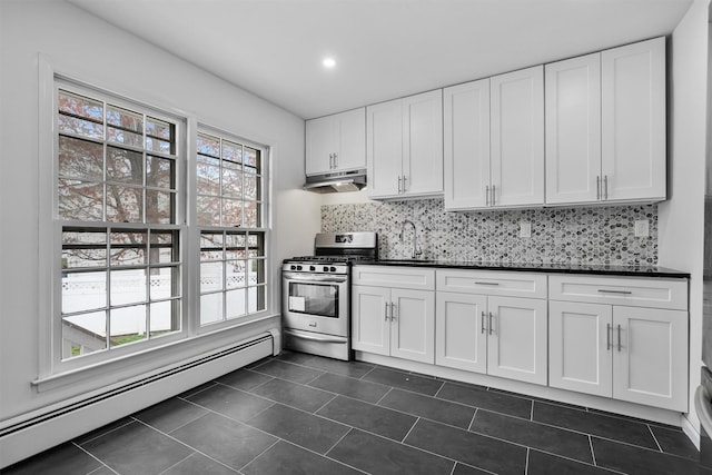 125 Lakewood Dr, Congers, NY 10920 - kitchen with stainless steel gas stove, baseboard heating, under cabinet range hood, dark countertops, and tasteful backsplash