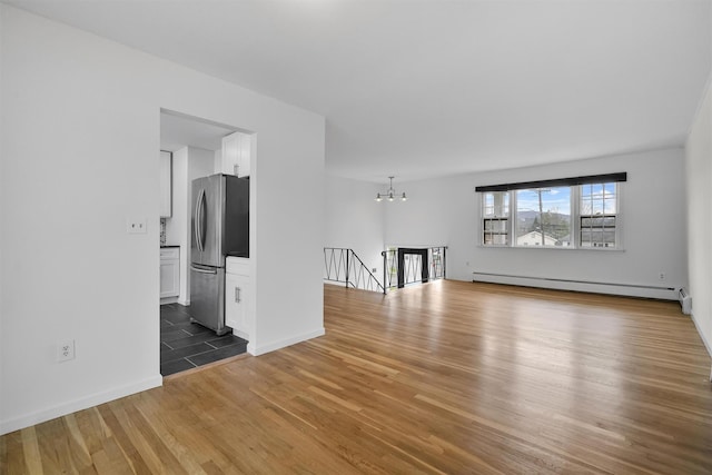 125 Lakewood Dr, Congers, NY 10920 - unfurnished living room with a baseboard radiator, wood finished floors, and a chandelier