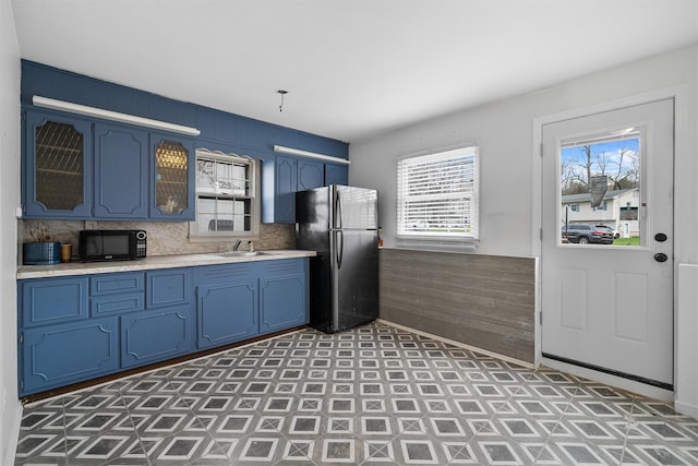 125 Lakewood Dr, Congers, NY 10920 - kitchen featuring freestanding refrigerator, blue cabinets, black microwave, light countertops, and wooden walls